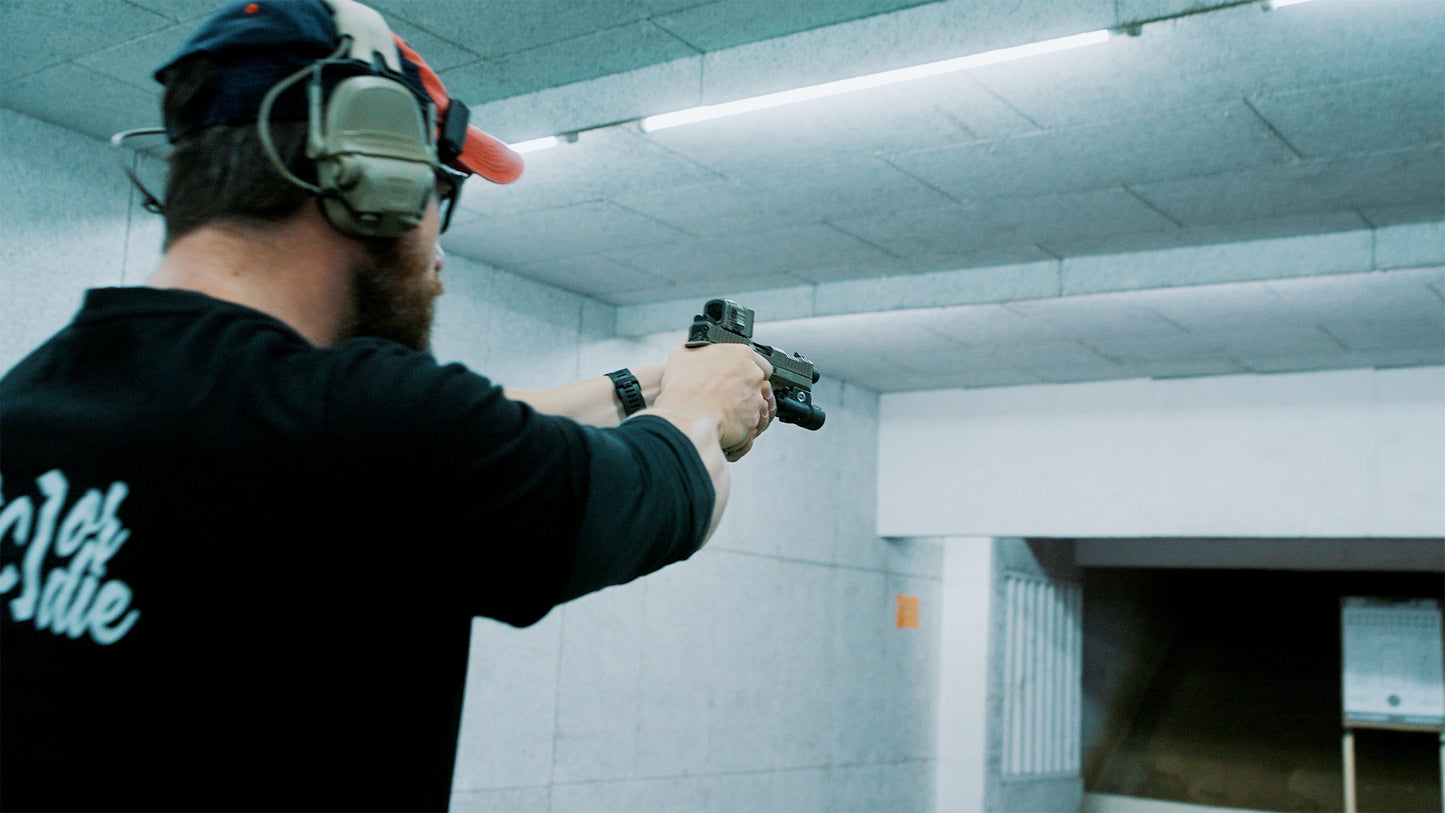 A man with hearing protection, cap, and glasses participates in the 11+12.07.26 - Pistole Level 3 Weekend - Fortgeschrittenen Kurs - Bad Soden bei Frankfurt (Mit Moritz), aiming his handgun at a target in a soundproof indoor shooting range.
